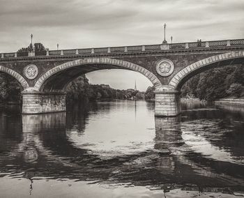 Arch bridge over river against sky