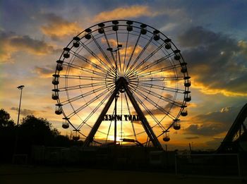 Low angle view of ferris wheel against cloudy sky