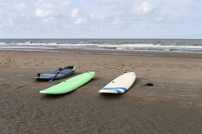 The photo shows a few surfboards on a sandy beach at the north sea