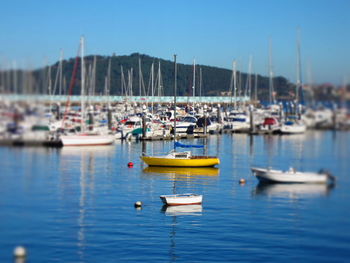 Tilt-shift image of boats moored on sea against clear sky