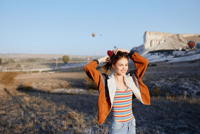 Young woman standing against sky