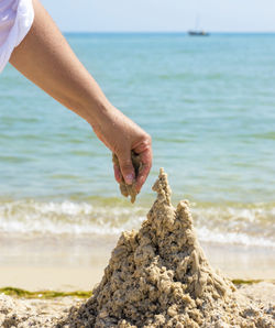 Cropped hand making sandcastle at beach