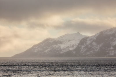 Scenic view of sea by mountains against sky