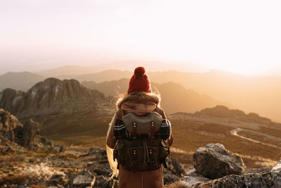 Rear view of man standing on mountain against sky