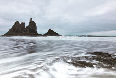 Scenic view of rocks in sea against sky