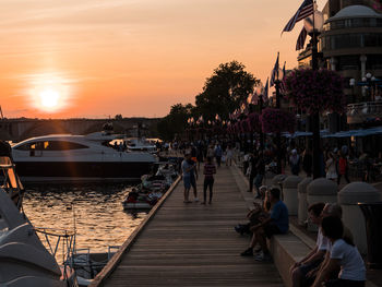 People on boats in sea against sky during sunset