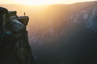 Scenic view of man looking out over mountains at sunset