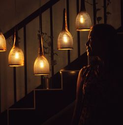 Woman in illuminated electric lamp at home