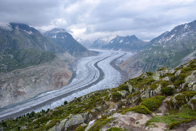 Aerial view of glaciers amidst mountains against cloudy sky