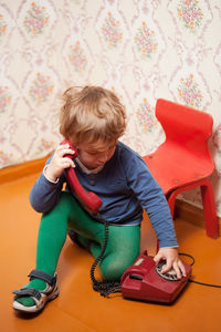 High angle view of cute boy dialing on rotary phone at home