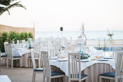 Chairs and tables at restaurant against sky