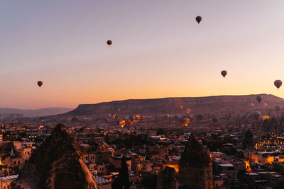 Hot air balloons in city against sky during sunset