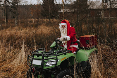 Man wearing santa costume riding lawn mower