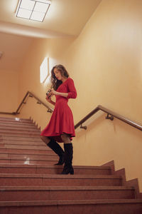 Low angle view of woman standing looking at camera while standing on staircase