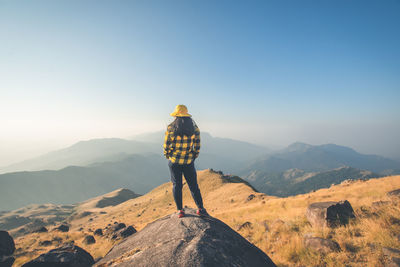 Rear view of man standing on mountain against sky