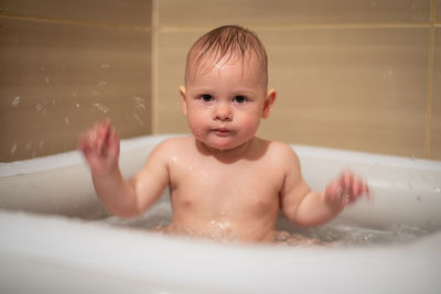 Portrait of cute boy sitting in bath