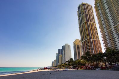 Modern buildings by sea against clear sky