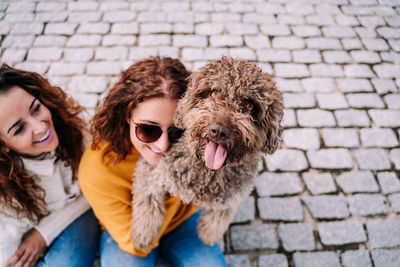 Portrait of young woman with dog on cobblestone