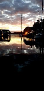 Silhouette boats in lake at sunset