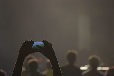 Cropped hands of person photographing concert through c