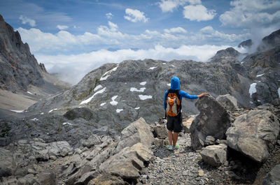 Rear view of man standing on rock at mountain