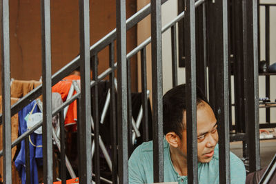 Portrait of young man looking at metal grate