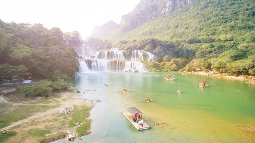 People enjoying in river against mountains