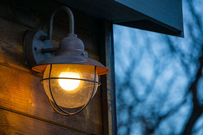 Low angle view of illuminated light mounted on cottage wall