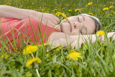 Woman holding flowers while lying on grass