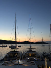 Sailboats moored at harbor against clear sky during sunset