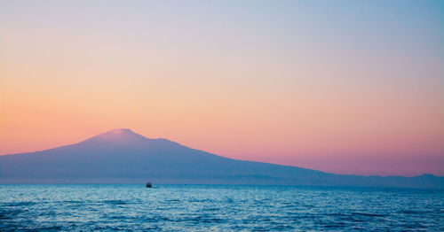 Scenic view of sea by mount etna against sky during sunset