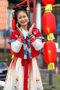 Portrait of smiling young woman standing against wall