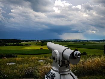 Close-up of car on landscape against cloudy sky