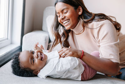 Happy smiling laughing indian mother playing with black baby girl daughter. family mixed race people 