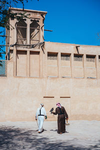 Rear view of man walking against building