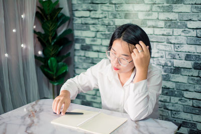 Woman looking away while sitting on table