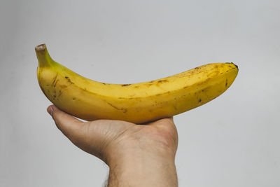 Close-up of hand holding apple against white background