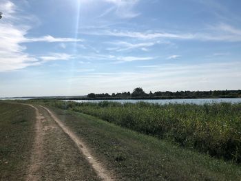 Road amidst field against sky