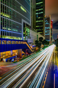 Light trails on city street by buildings at night