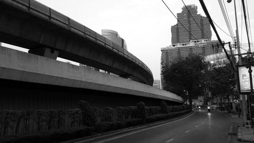 Road by bridge in city against sky