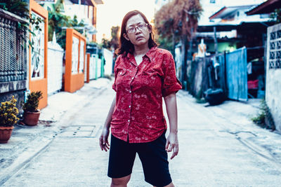 Portrait of young woman standing on street in city