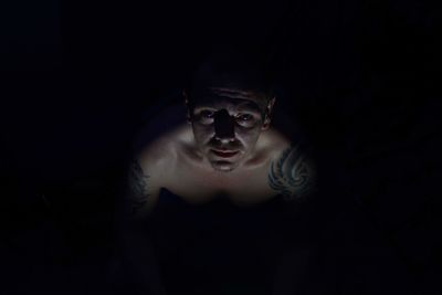 Portrait of shirtless man in darkroom