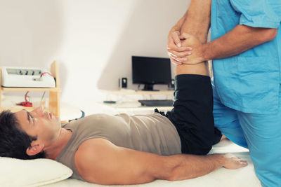 Man receiving massage therapy while lying on bed