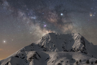 Scenic view of snowcapped mountains against sky at night