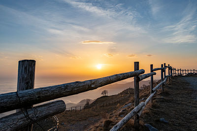 Wooden posts on mountain linzone against sky during sunset