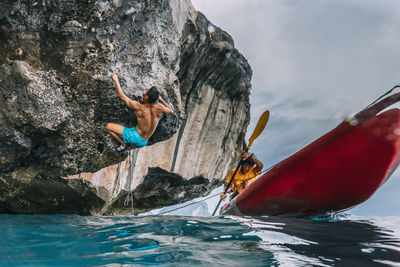 People in sea by rock formation