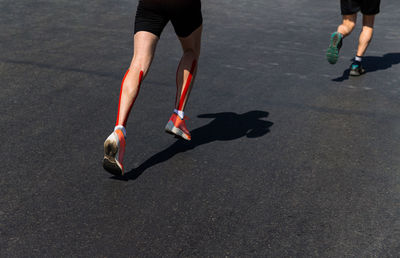 Legs two male runners run marathon on dark asphalt