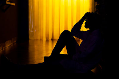 Side view of silhouette man sitting on stage