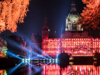 Illuminated church reflecting on calm lake against sky at night