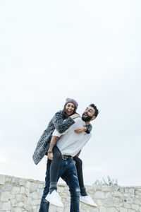 Portrait of young couple standing against clear sky